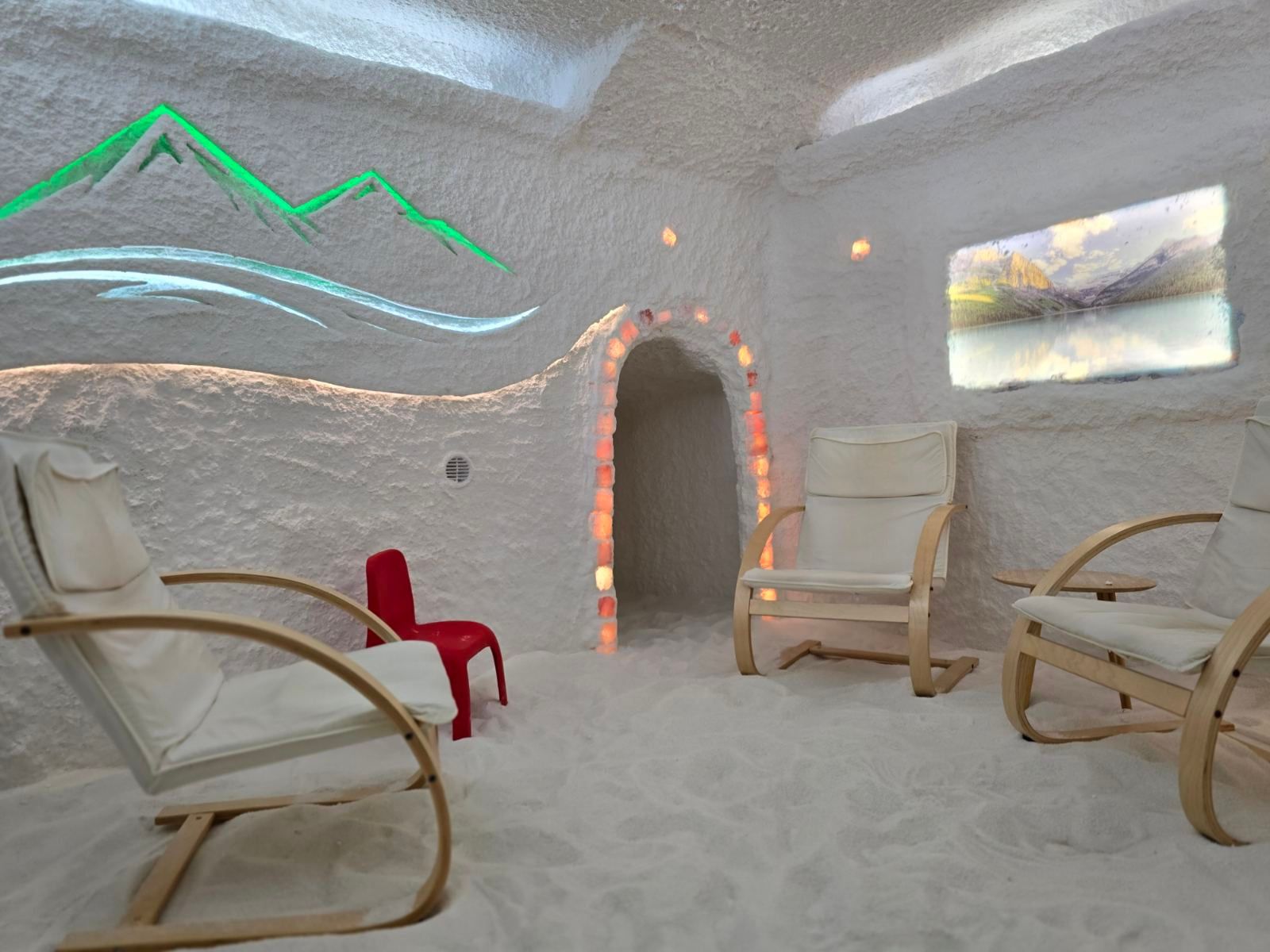 A salt room with loungers, a salt archway and a wall mural