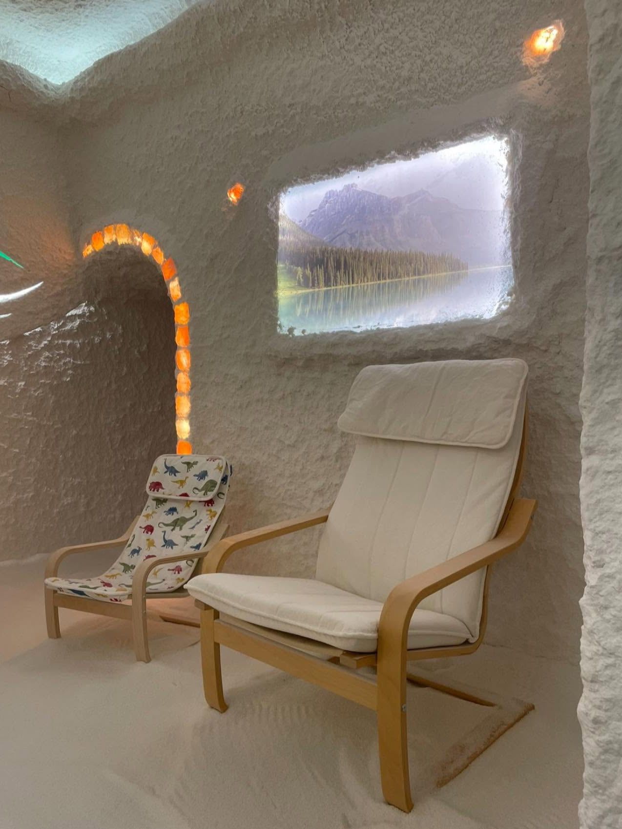 A salt room with a lounger, a child’s seat and an illuminated salt archway