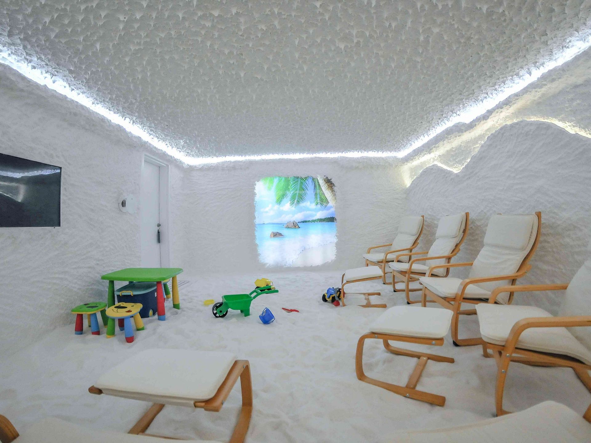 Family salt room with wooden loungers, a children’s corner and a backlit ceiling